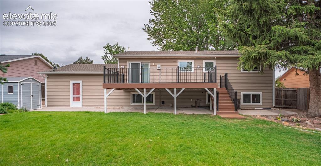 Image 31 of 34: Expansive grassy backyard featuring a multi-level deck with black railings,