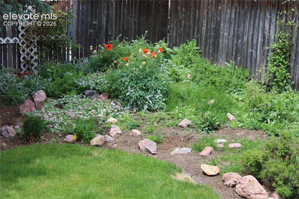 Image 33 of 34: Garden area featuring established plantings, natural stone accents, and a w