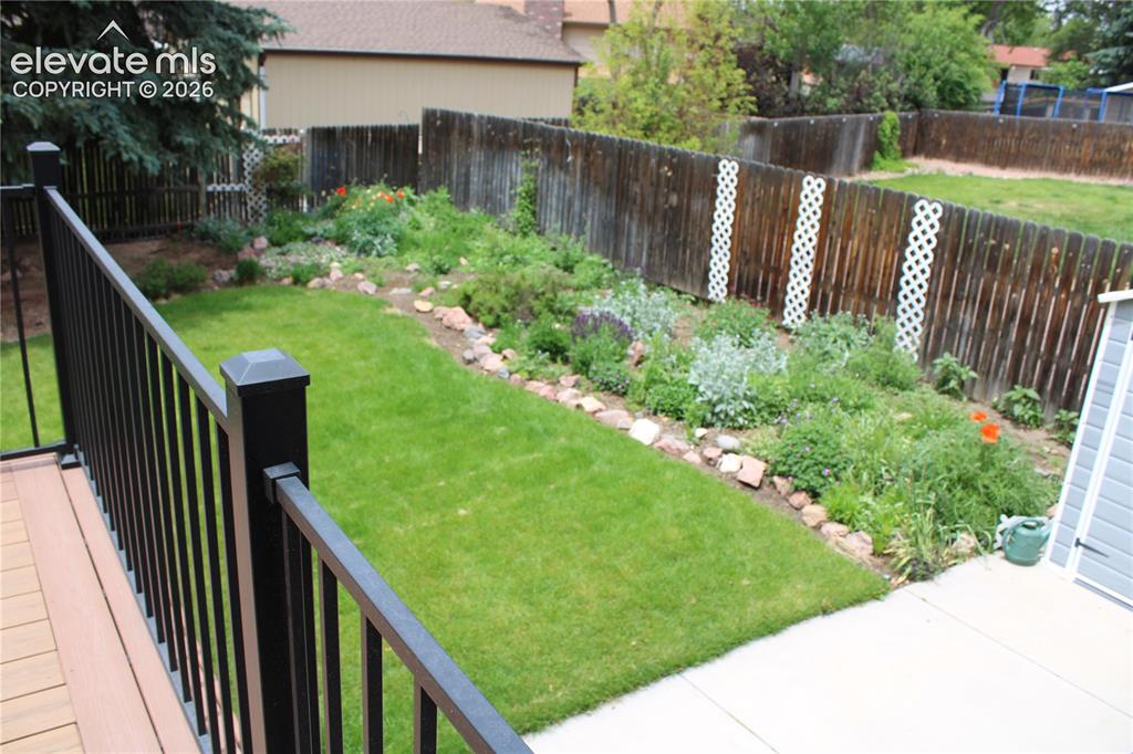 Image 34 of 34: Private backyard featuring a well-maintained lawn, established garden beds,