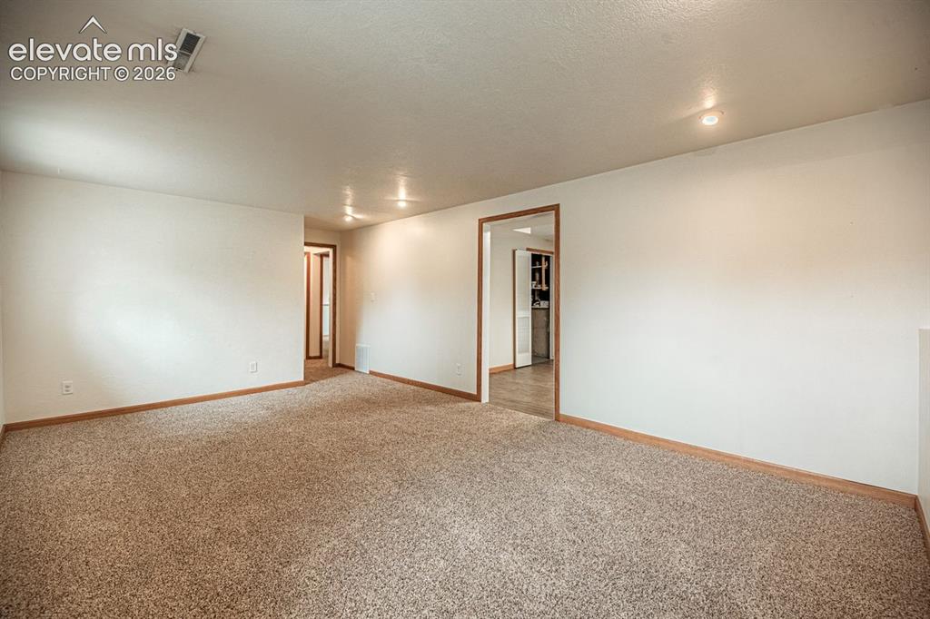 Image 8 of 34: Spacious interior featuring neutral carpet flooring, light-toned walls, and