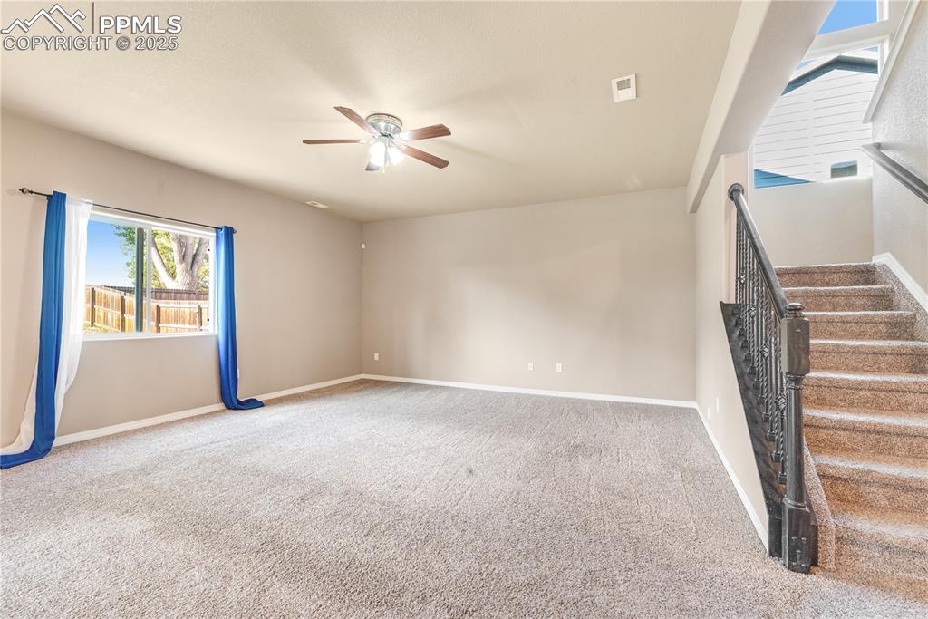 Image 13 of 43: Unfurnished living room featuring carpet, ceiling fan, and stairs