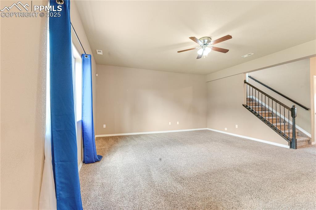 Image 15 of 43: Unfurnished room with carpet flooring, stairs, and ceiling fan
