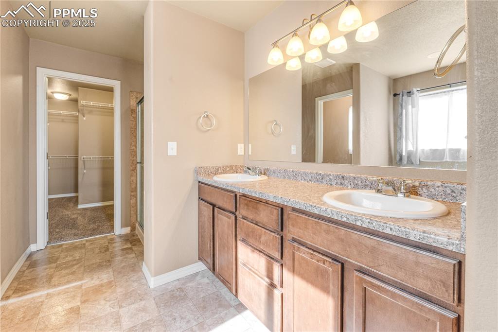 Image 21 of 43: Full bath featuring double vanity, a stall shower, and a spacious closet