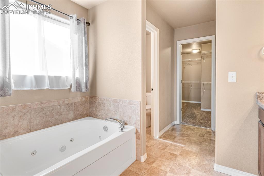 Image 22 of 43: Bathroom featuring a jetted tub, vanity, and a spacious closet