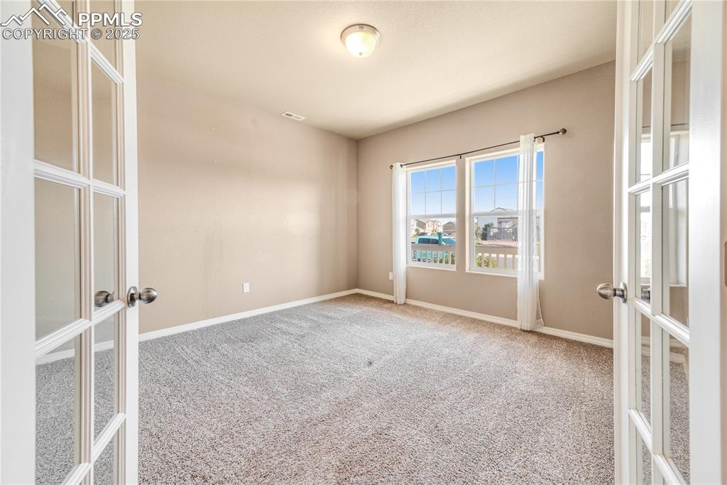 Image 37 of 43: Carpeted empty room with french doors and baseboards