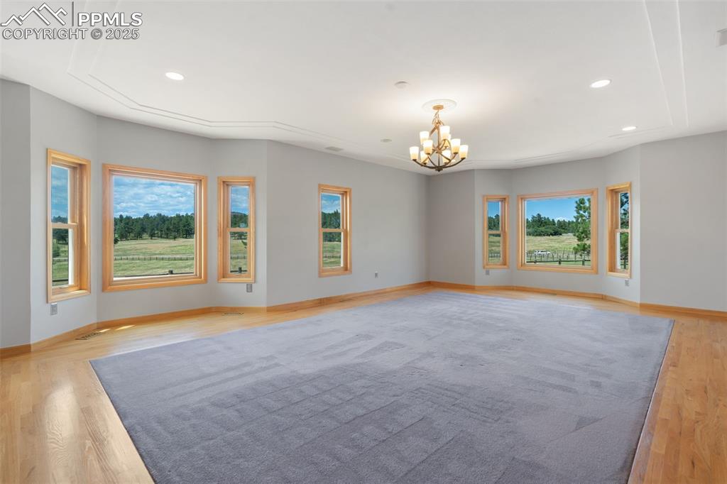 Image 18 of 50: Unfurnished room with a chandelier, light wood-type flooring, and recessed 