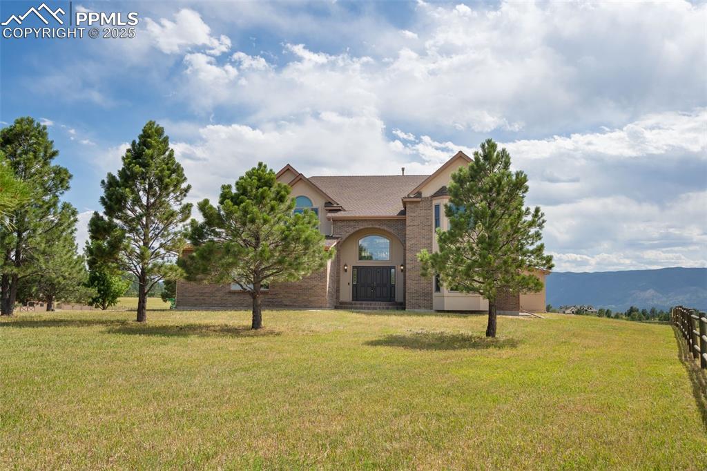 Image 2 of 50: View of front facade featuring a front yard, brick siding, and a shingled r