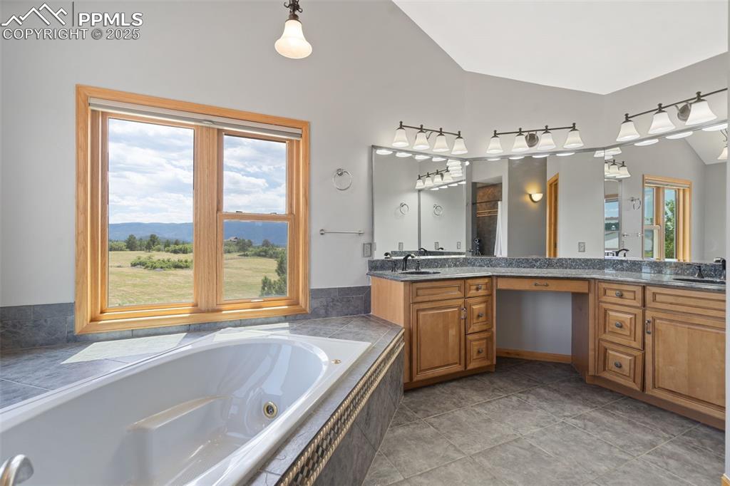 Image 23 of 50: Bathroom featuring vaulted ceiling, double vanity, and a jetted tub