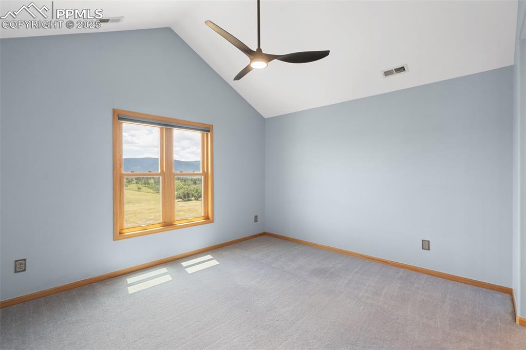 Image 28 of 50: Unfurnished room with ceiling fan, vaulted ceiling, and light carpet