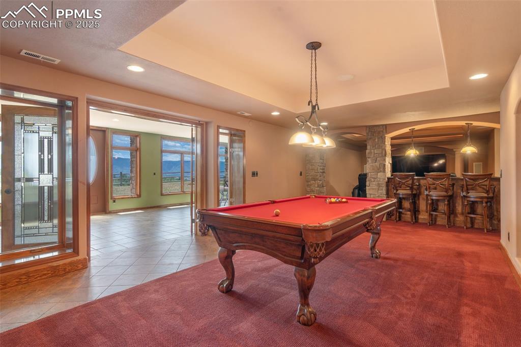 Image 35 of 50: Recreation room with a tray ceiling, tile patterned floors, billiards table