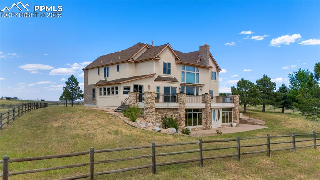 Image 40 of 50: Back of property with stucco siding, stone siding, a chimney, a fenced back