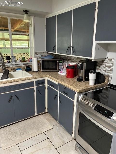 Image 5 of 18: Kitchen with stove, decorative backsplash, light countertops, and gray cabi