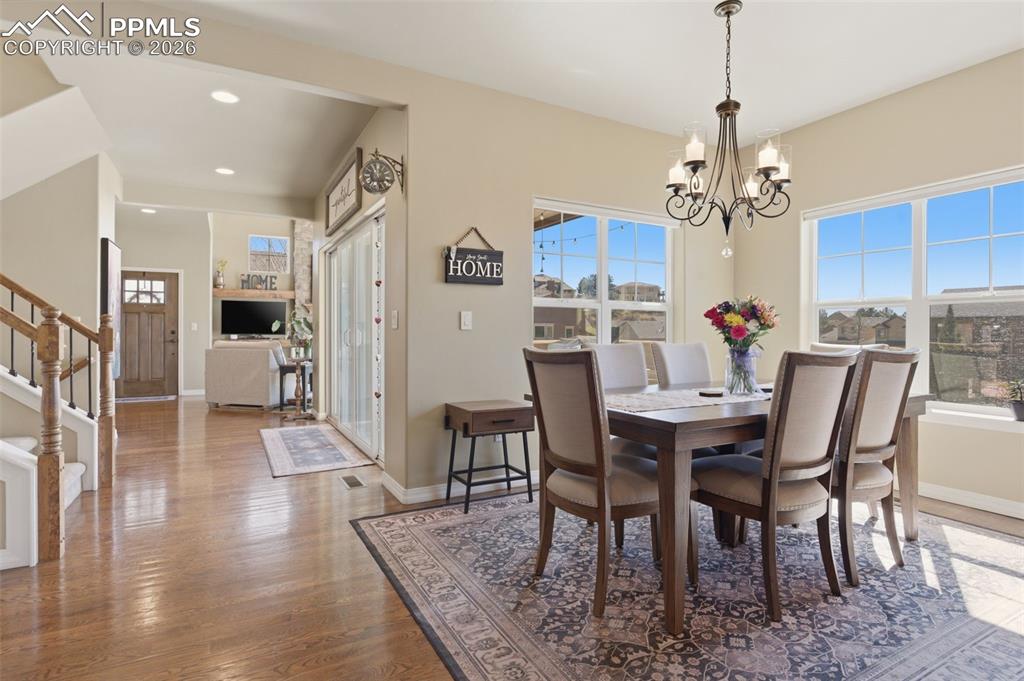 Image 12 of 50: Dining space with dark wood-style flooring, a large fireplace, and recessed