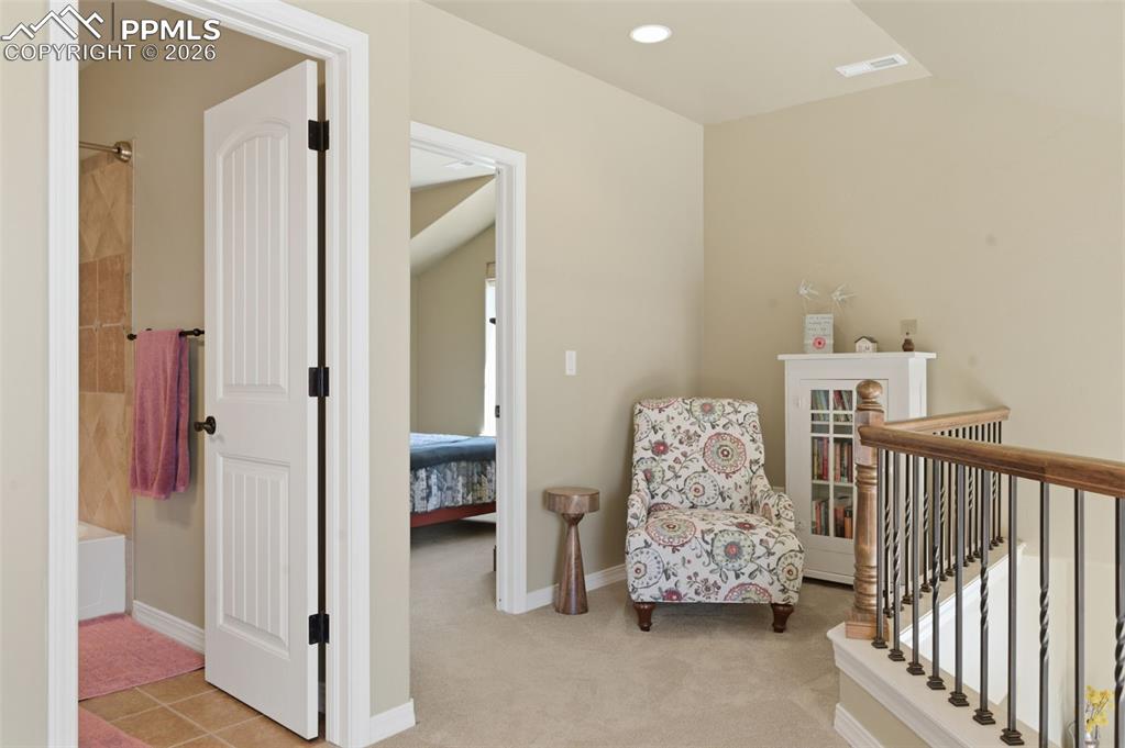 Image 27 of 50: Bedroom with connected bathroom, light carpet, and a ceiling fan
