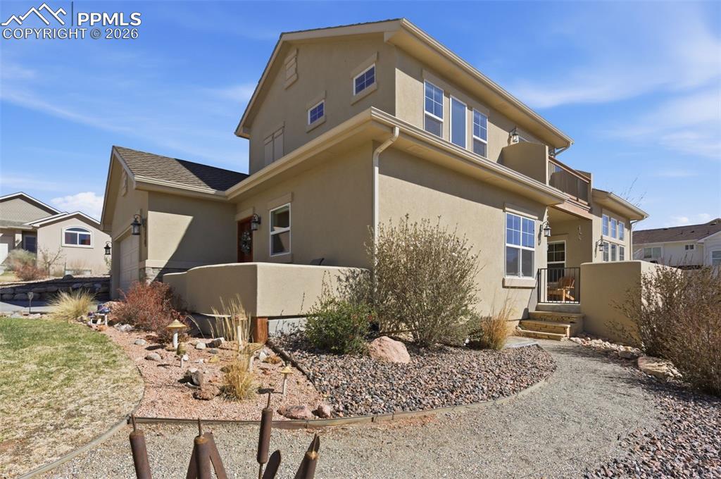 Image 42 of 50: View of front facade with stucco siding, a garage, concrete driveway, stone