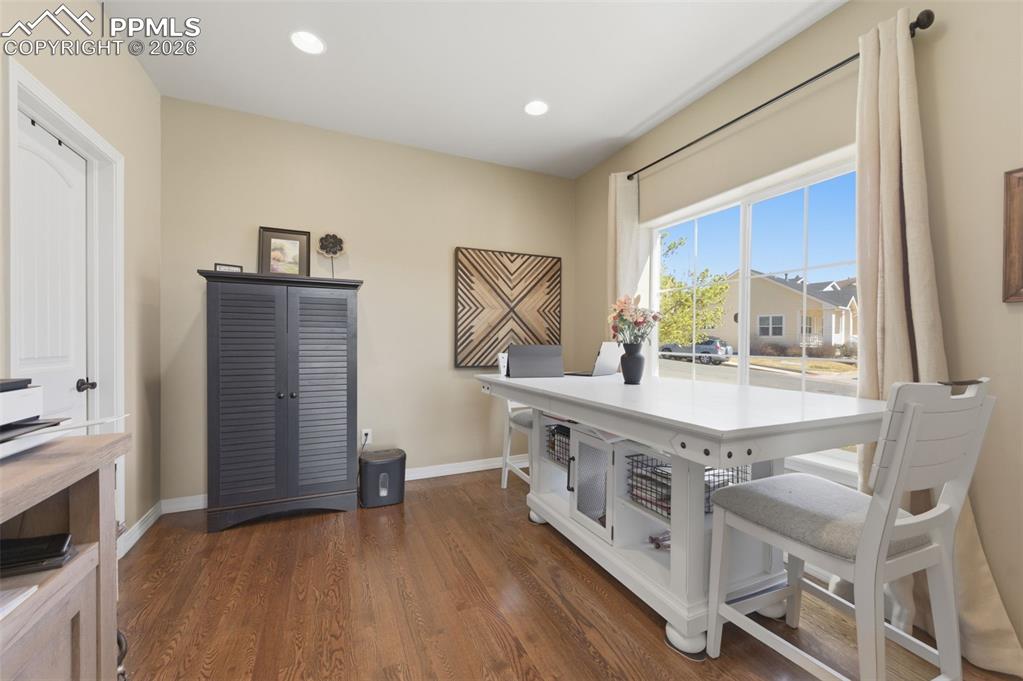 Image 7 of 50: Living room featuring a stone fireplace, hanging lights, wood finished floo