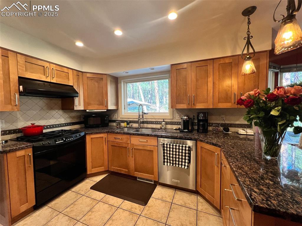 Image 10 of 49: Kitchen with black appliances, under cabinet range hood, a sink, decorative