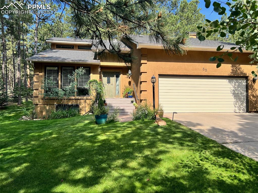Image 2 of 49: View of front of property with driveway, a front yard, stucco siding, and a