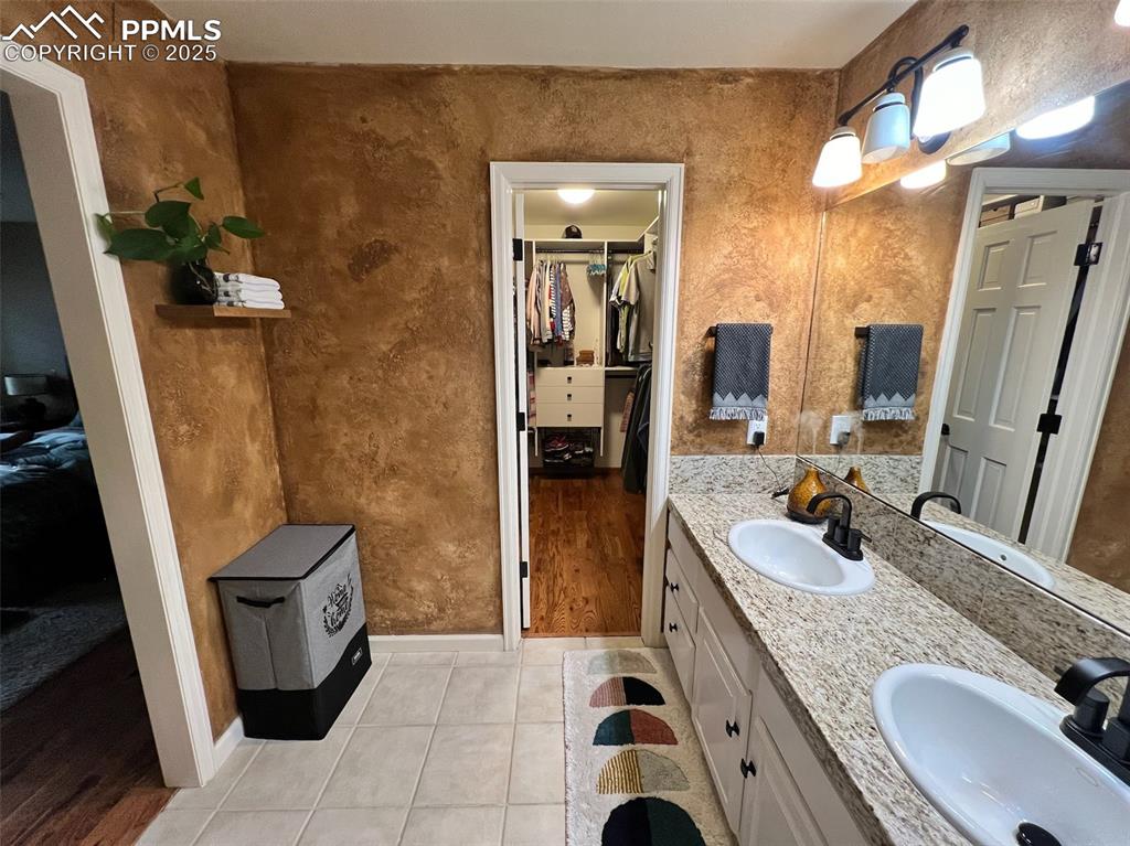 Image 21 of 49: Bathroom featuring a walk in closet, tile patterned floors, double vanity,