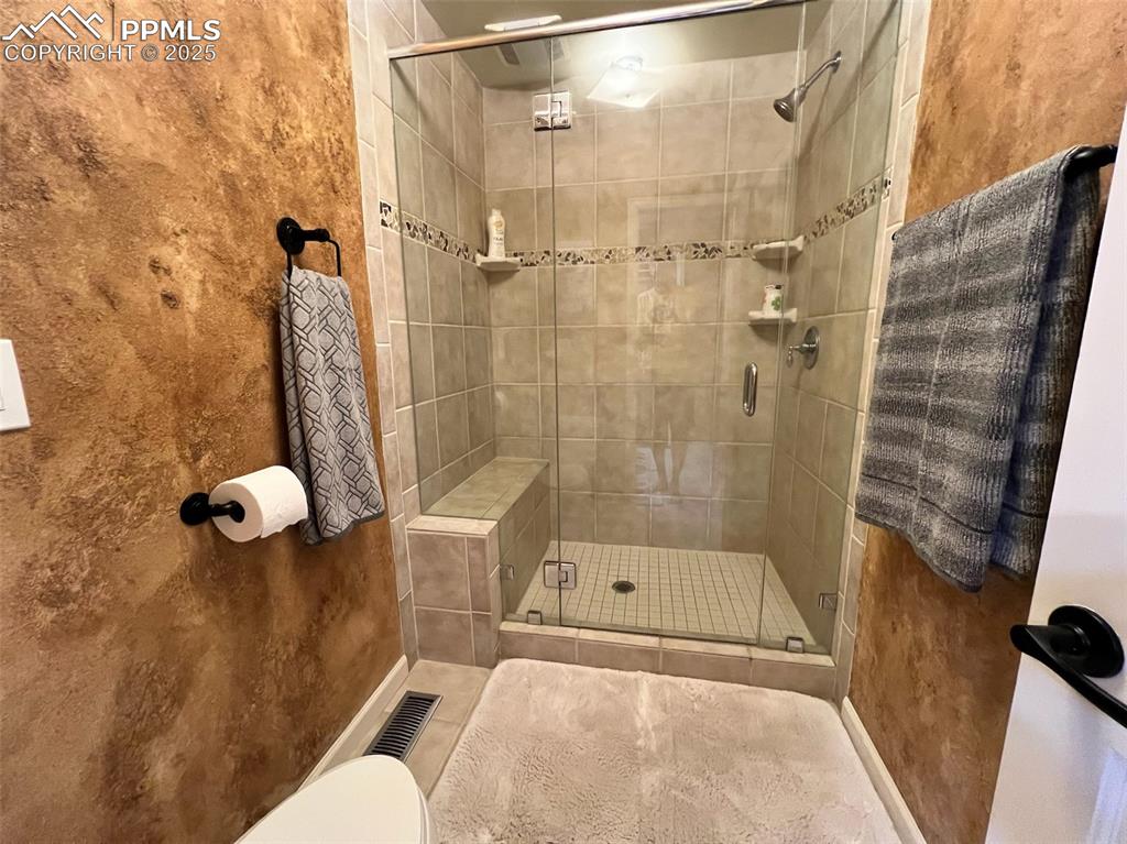 Image 23 of 49: Full bathroom with a shower stall and toilet