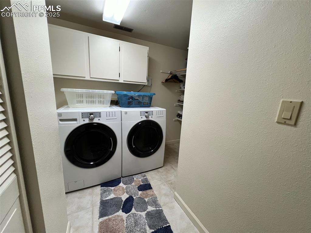 Image 33 of 49: Washroom with washing machine and clothes dryer, light tile patterned floor
