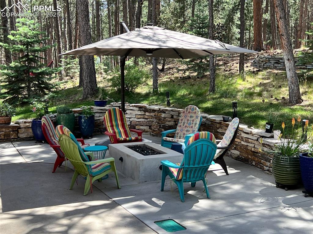 Image 34 of 49: View of patio featuring a fire pit and a view of trees
