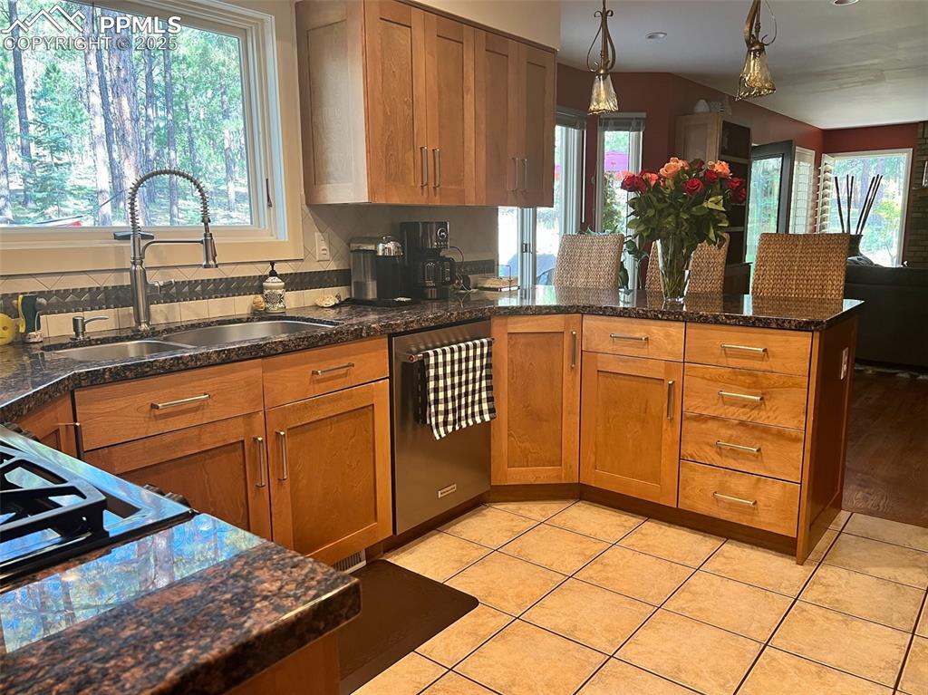 Image 9 of 49: Kitchen with stainless steel dishwasher, a sink, a peninsula, and plenty of