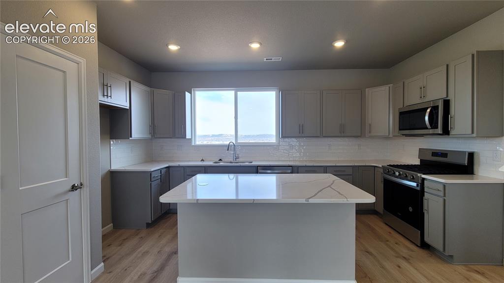 Image 10 of 26: Grand Kitchen with Quartz countertops, pantry, plenty of cabinets, island p