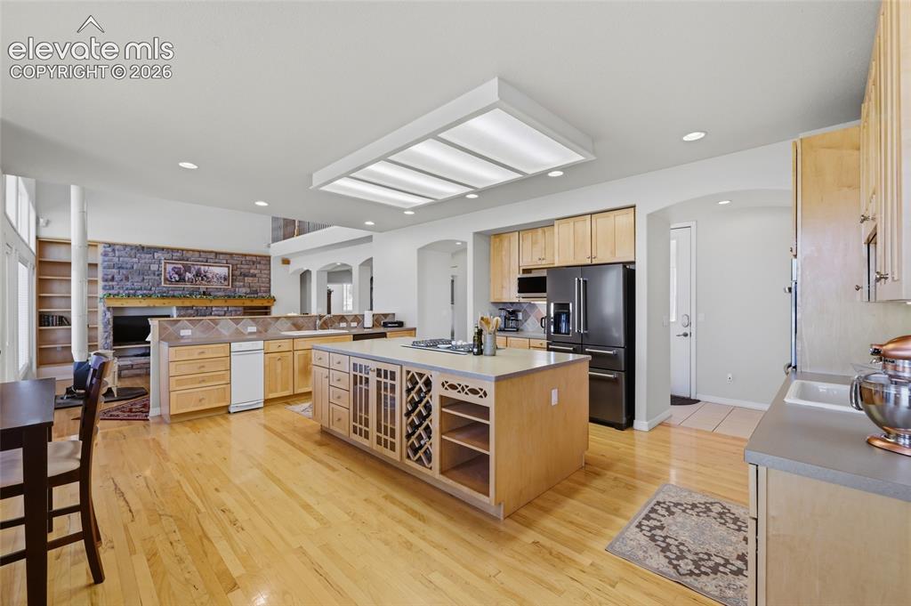 Image 27 of 50: Kitchen area featuring light wood cabinetry, a double basin sink, and a bla