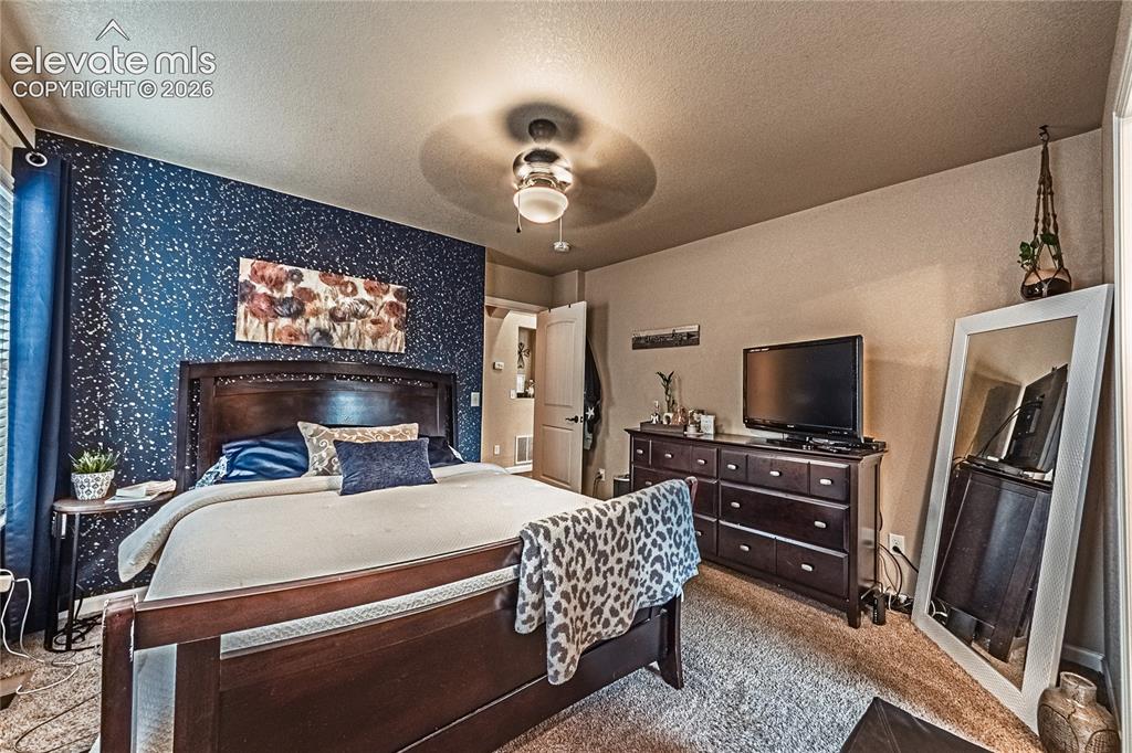 Image 15 of 36: Bedroom featuring ceiling fan, light colored carpet, a textured ceiling, an