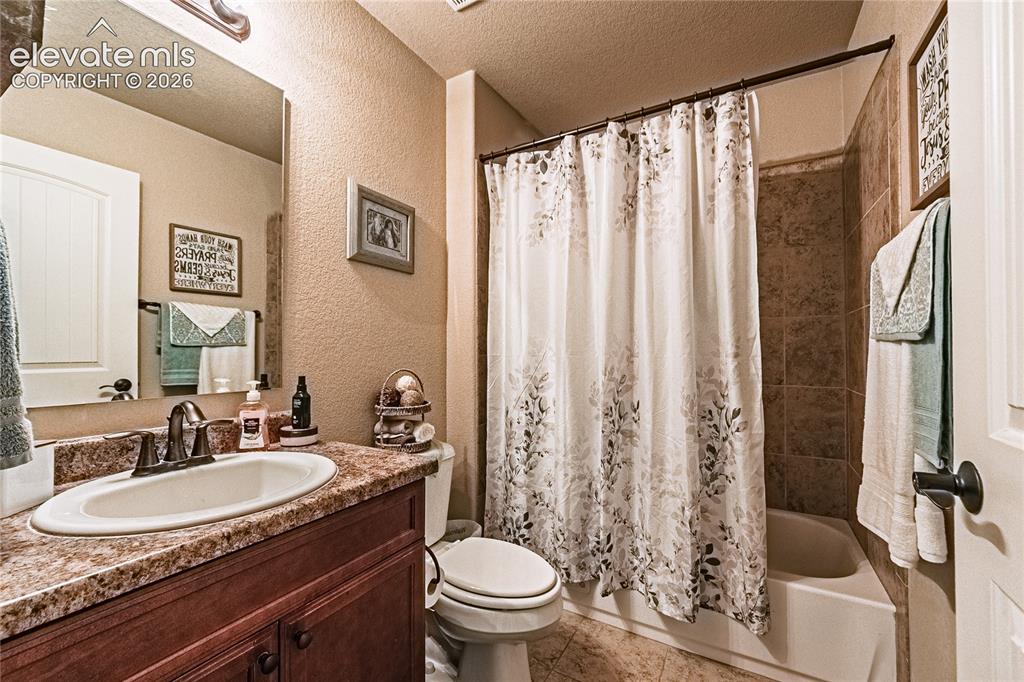 Image 19 of 36: Bathroom with a textured wall, a textured ceiling, shower / tub combo, vani