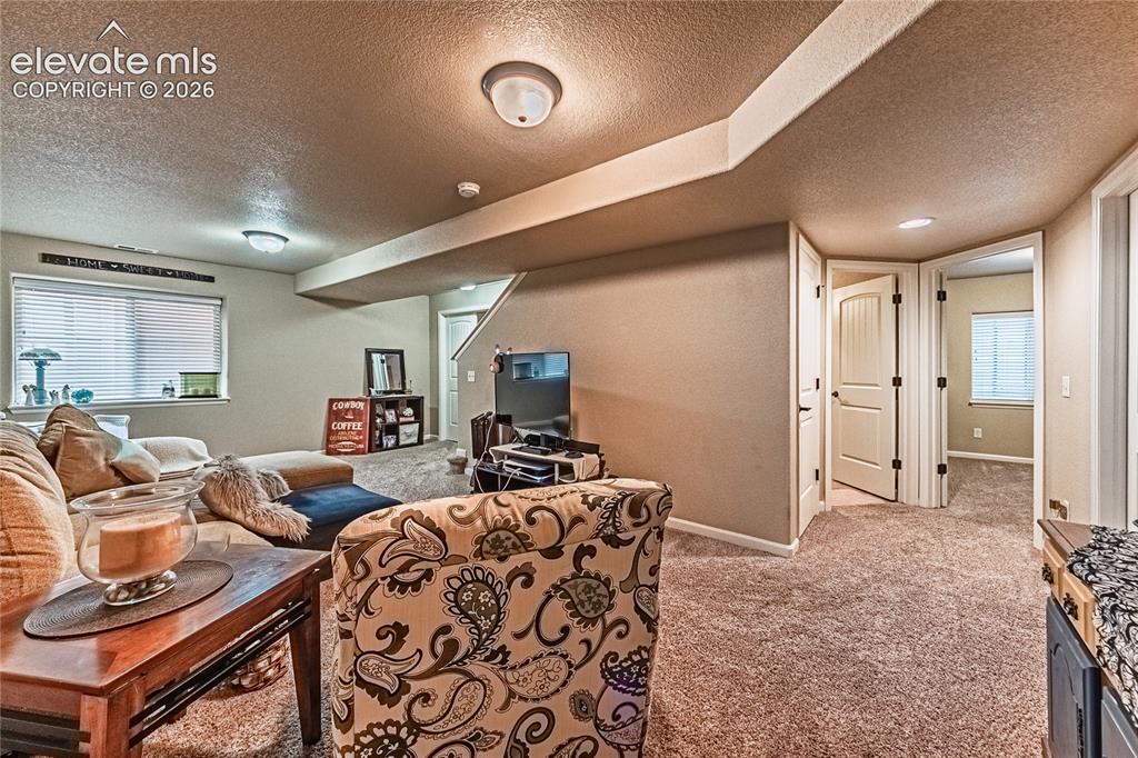 Image 23 of 36: Carpeted living area with a textured ceiling and baseboards
