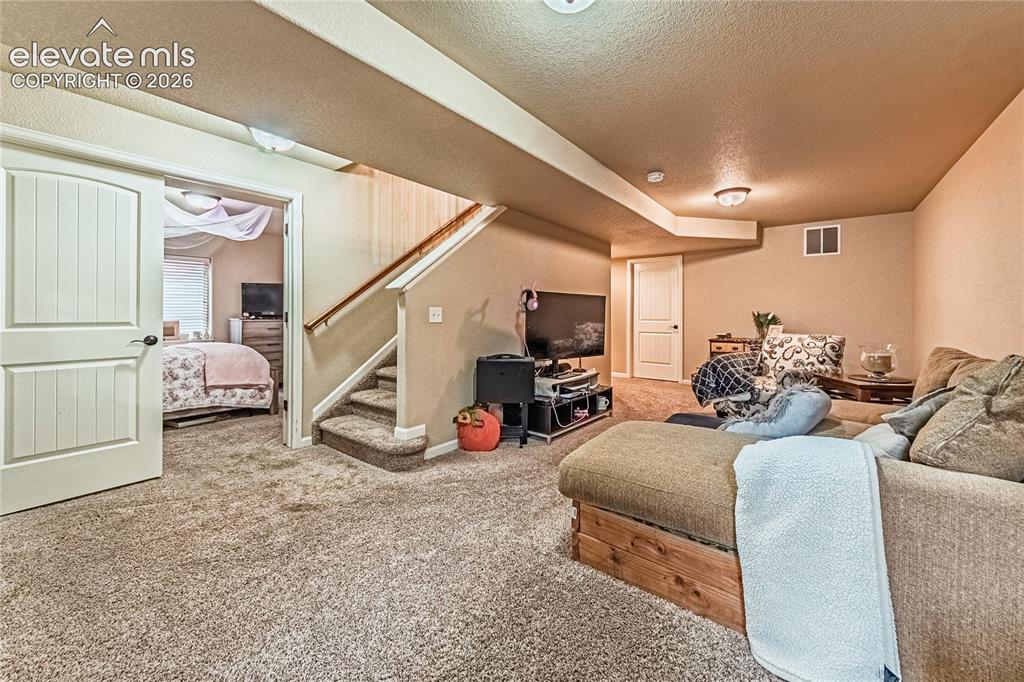 Image 25 of 36: Carpeted living room featuring stairway and a textured ceiling