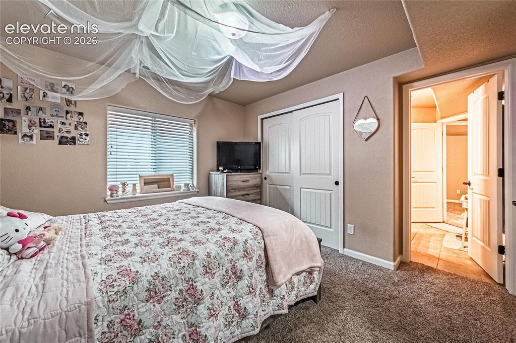 Image 27 of 36: Carpeted bedroom featuring a textured wall, a closet, and tile patterned fl