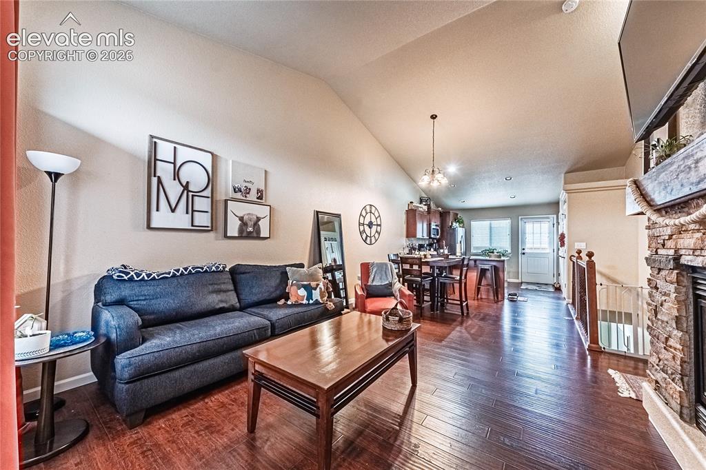 Image 4 of 36: Living area featuring dark wood-type flooring, a stone fireplace, and high