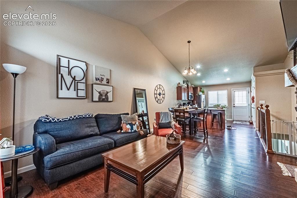 Image 6 of 36: Living room with dark wood-style floors, recessed lighting, and high vaulte