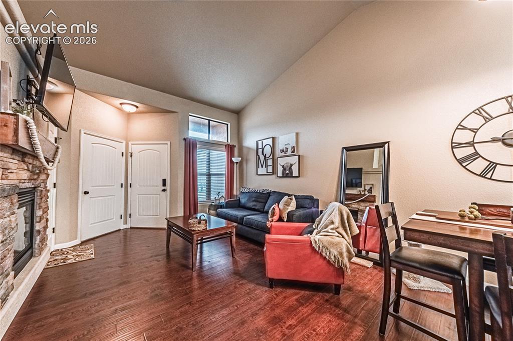 Image 7 of 36: Living area featuring dark wood finished floors, a stone fireplace, and hig