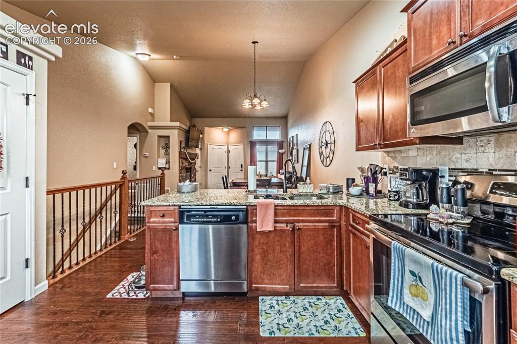 Image 9 of 36: Kitchen with appliances with stainless steel finishes, a peninsula, brown c