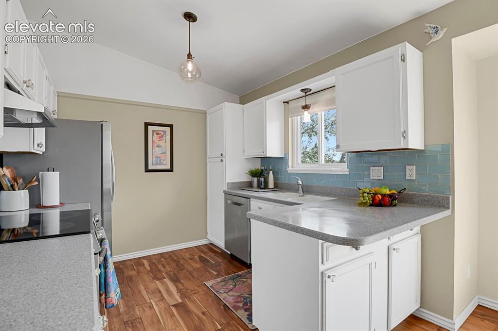 Image 10 of 38: Kitchen featuring white cabinetry, light gray countertops, and wood-finish 