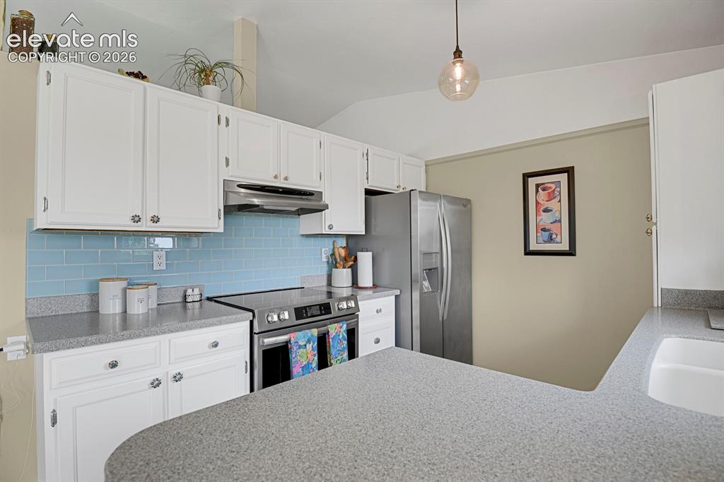 Image 11 of 38: White cabinetry with decorative hardware, light blue subway tile backsplash