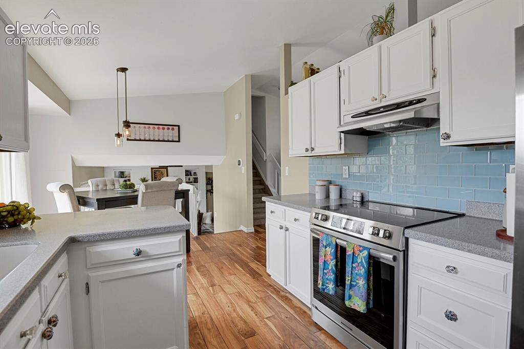 Image 12 of 38: White shaker-style cabinetry, wood-finish flooring, stainless steel applian