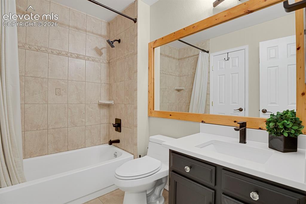 Image 17 of 38: Built-in tub with tile surround, wood-framed mirror, vanity with dark cabin