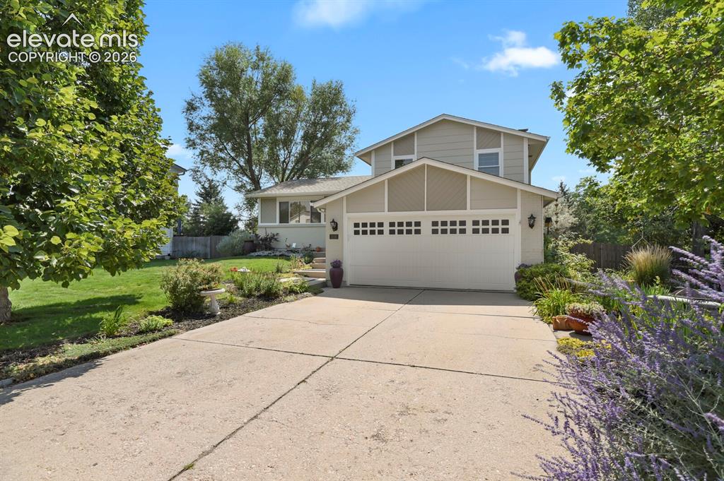 Image 2 of 38: Split-level residence featuring a concrete driveway, attached two-car garag