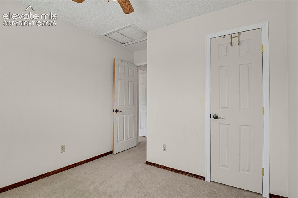 Image 21 of 38: Light-toned carpeted flooring, wood-finish baseboards, white paneled doors,