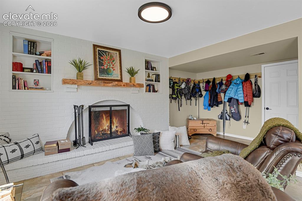 Image 23 of 38: White brick fireplace with a wood mantle and built-in shelving