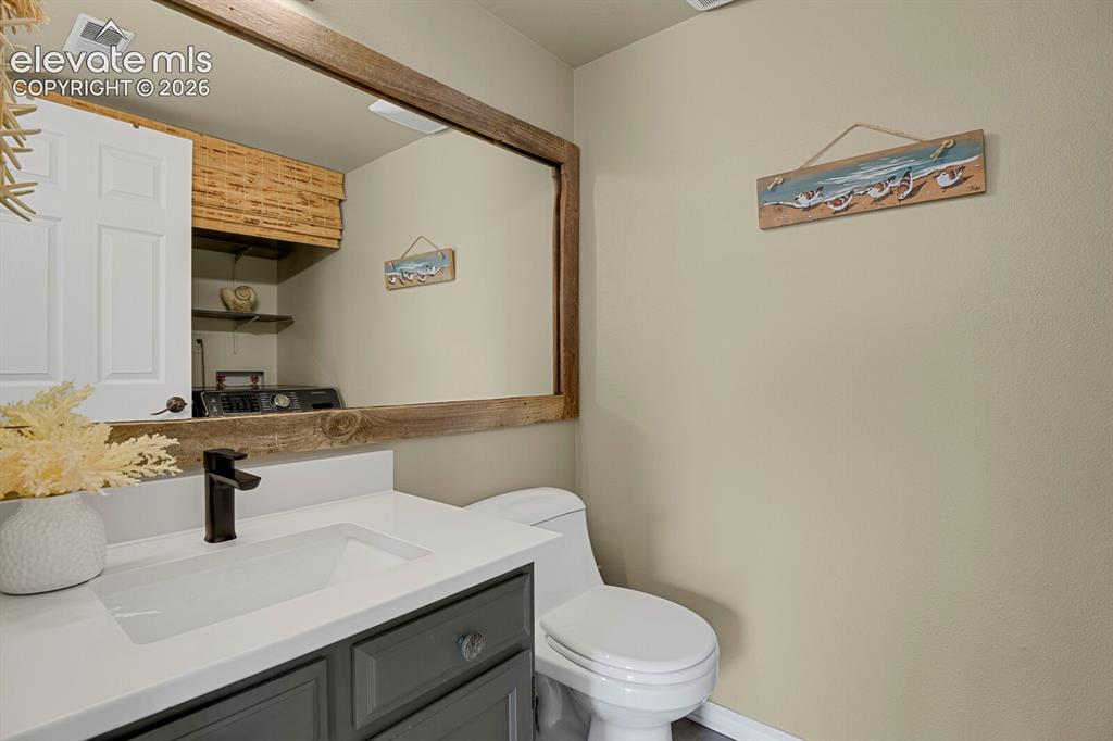 Image 26 of 38: Vanity with dark gray cabinetry and a white countertop with an integrated s