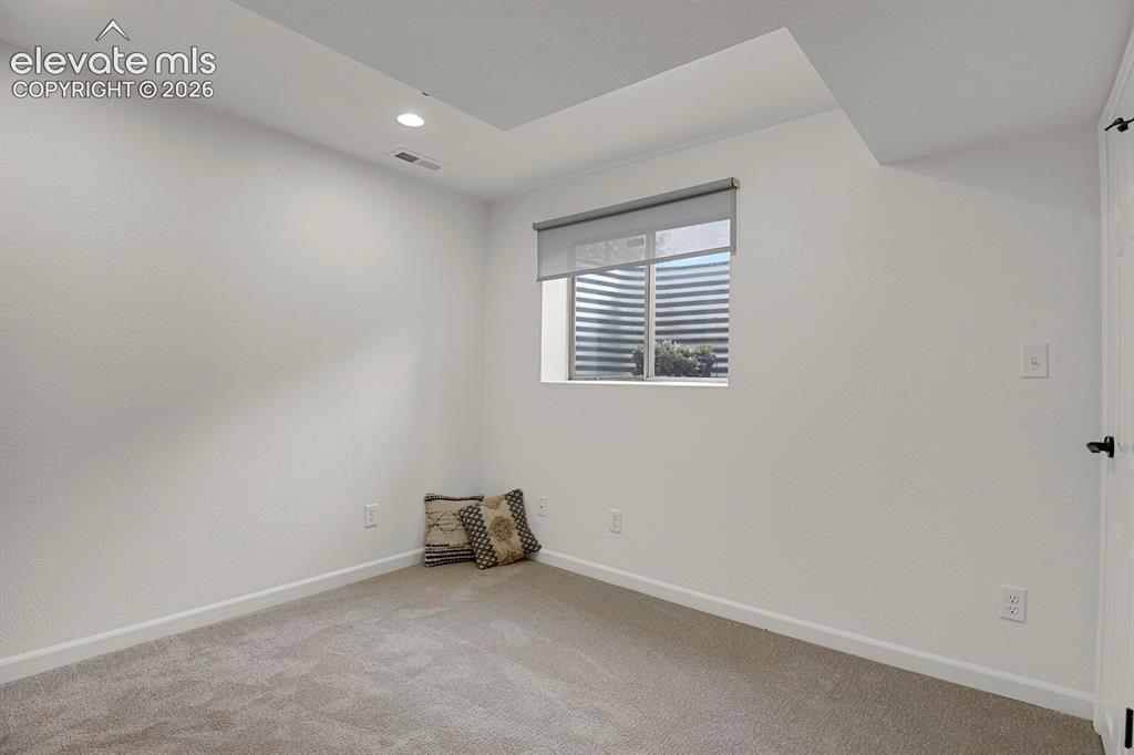 Image 32 of 38: Recessed lighting, light-toned carpeting, and a window with a roller shade