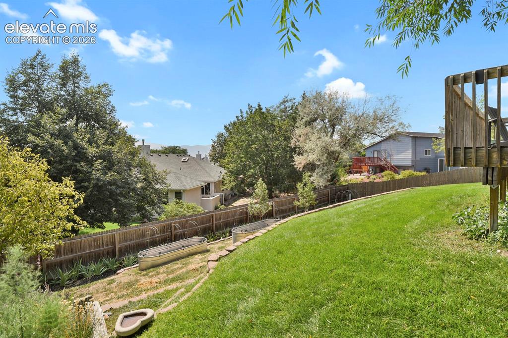 Image 36 of 38: Expansive grassy slope with a wood privacy fence and established trees