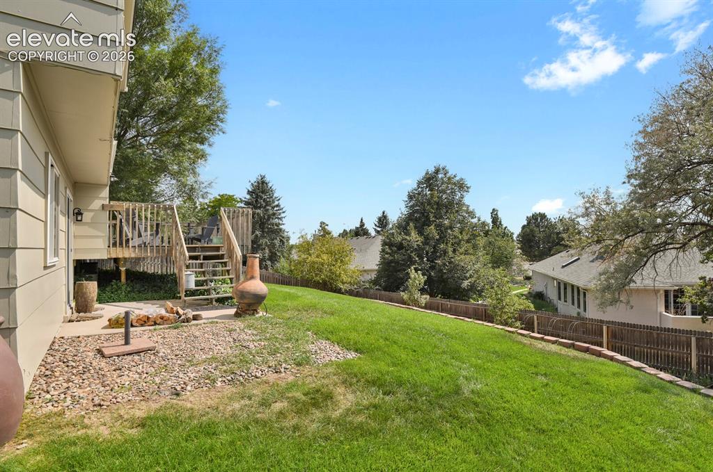 Image 37 of 38: Expansive lawn area with a multi-level wood deck featuring railings and sta