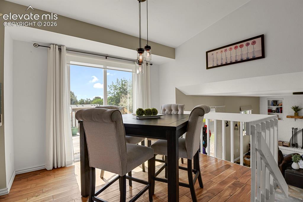 Image 8 of 38: Hardwood flooring, sliding glass door, white painted railing, cathedral cei